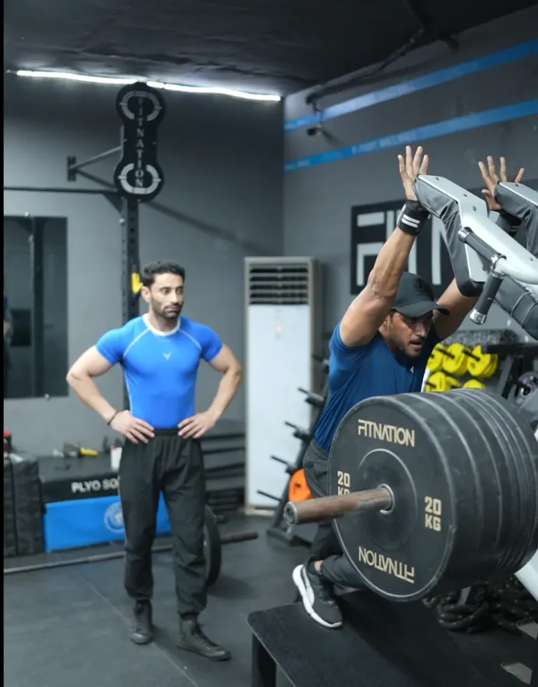Coach watching a member step up onto a box next to Fitnation-branded plates