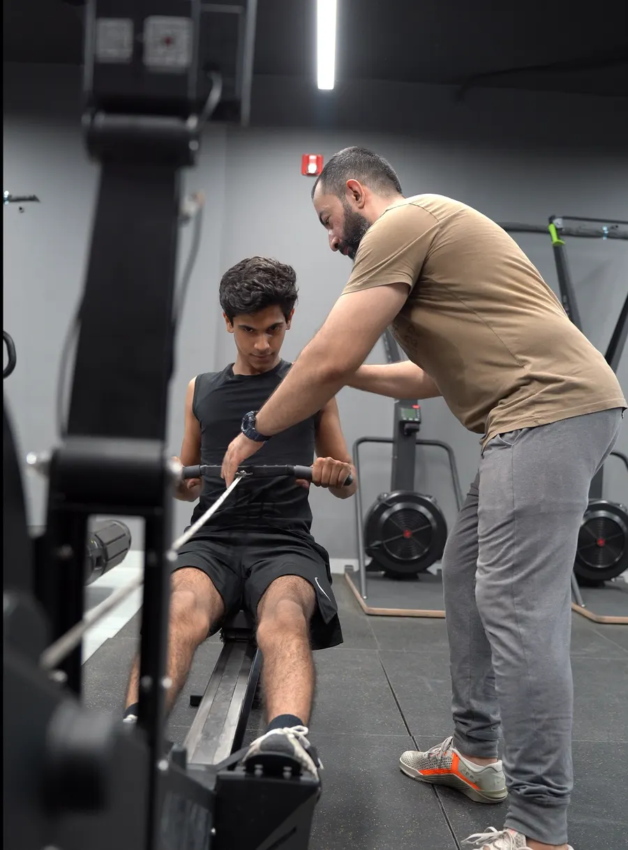 Coach correcting a member’s form on a cable row at Fitnation Gym