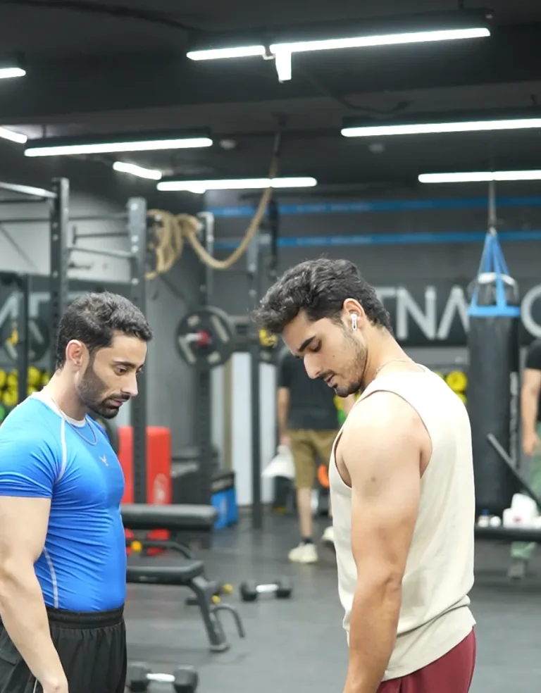 Coach talking a member through technique on the gym floor at Fitnation Gym