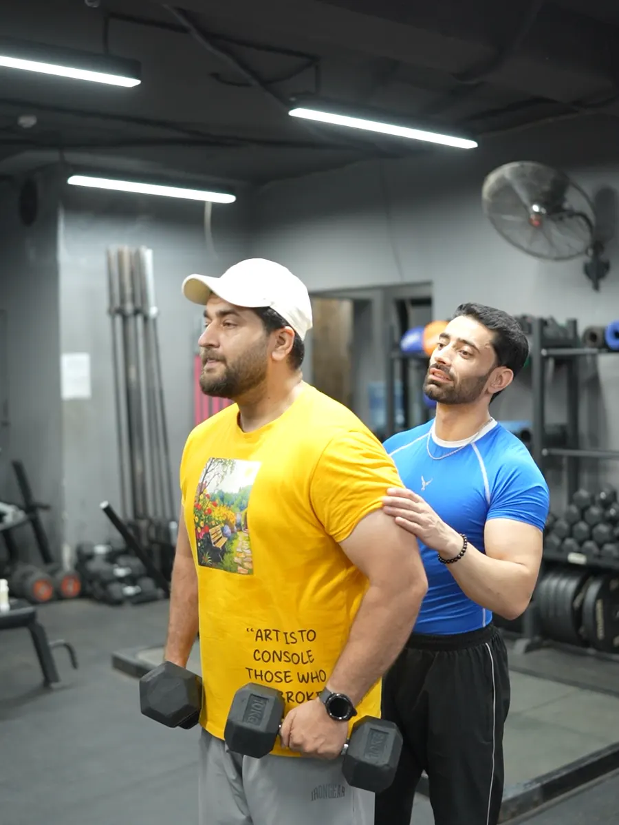 Coach guiding a member through a dumbbell exercise at Fitnation Gym